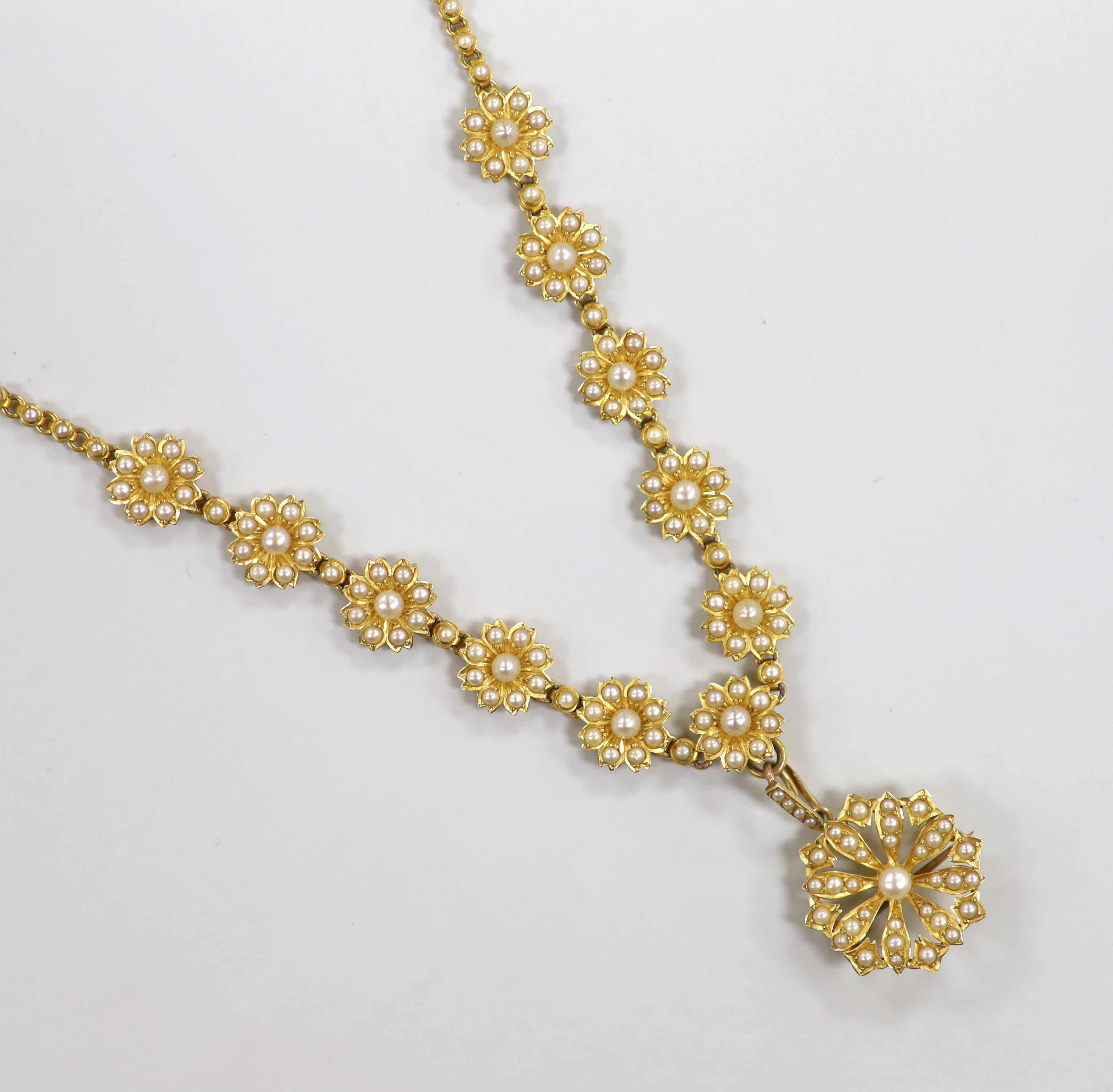 An Edwardian yellow metal and seed pearl set pendant brooch necklace, with flower head motifs, 43cm, gross weight 23.4 grams.